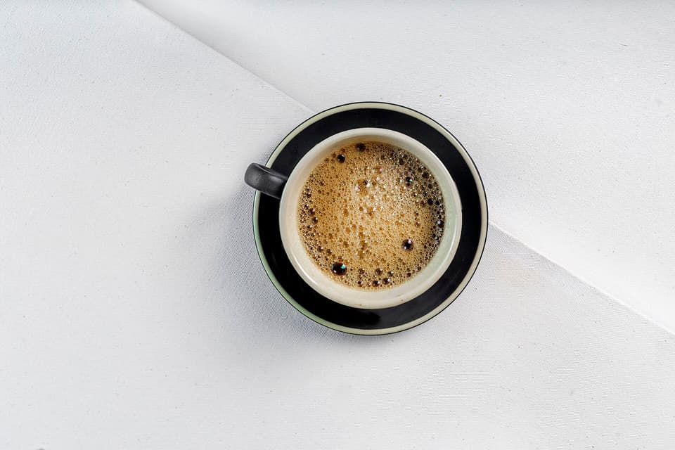 A small black espresso in a dark cup, seen from above on a white table (illustrative)