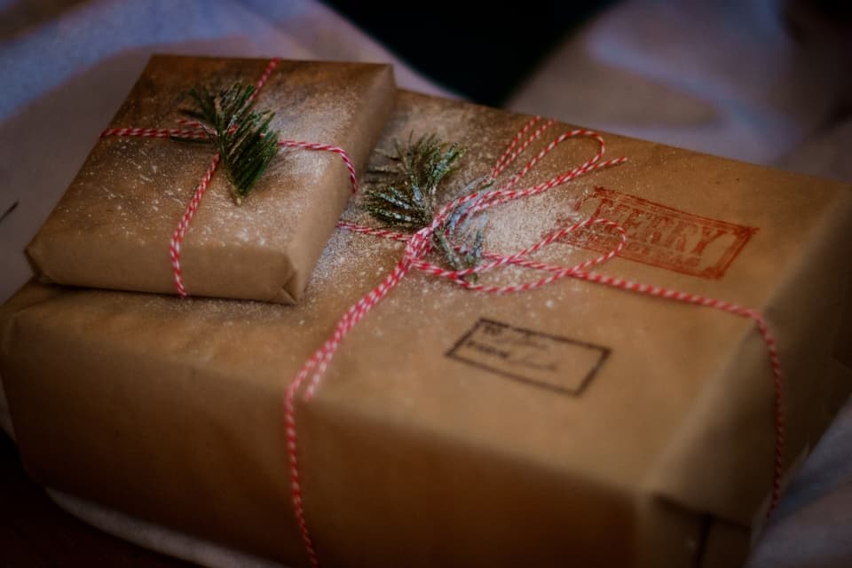 Presents wrapped in brown paper and red-and-white string with sprigs of pine (illustrative)