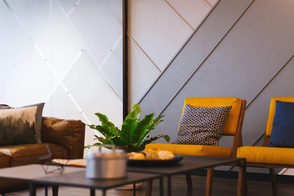 A calm office lounge with a leather sofa, two yellow chairs and a plant (illustrative)